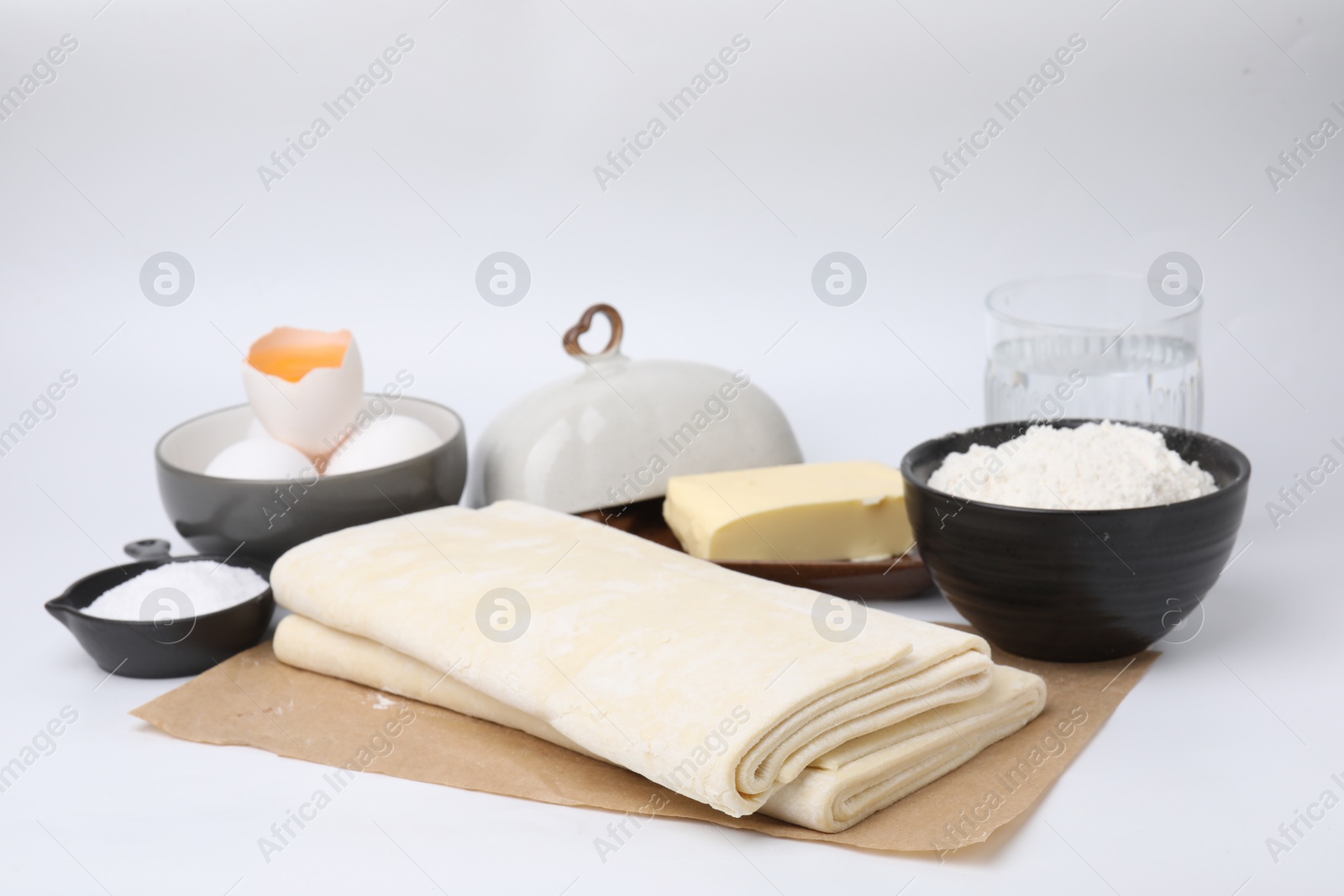 Photo of Raw puff pastry dough and ingredients isolated on white