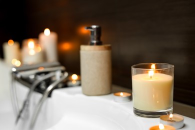 Photo of Burning candles on edge of bath indoors, closeup. Romantic atmosphere
