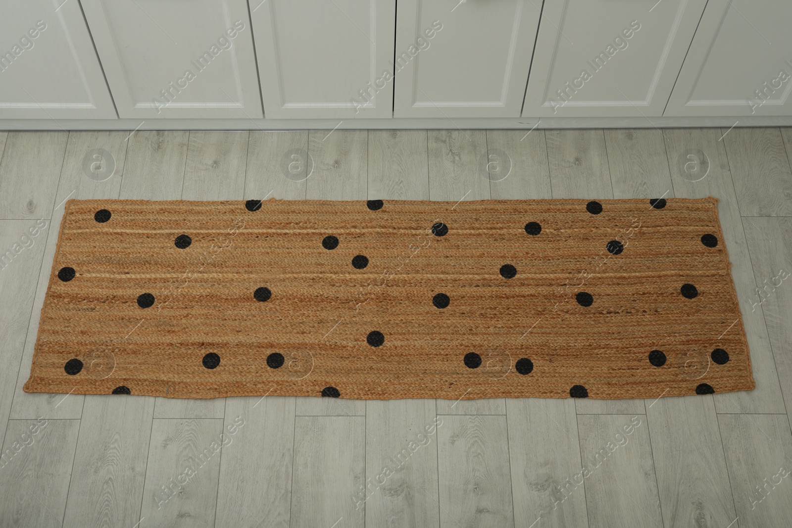 Photo of Stylish rug with dots on floor in kitchen, above view