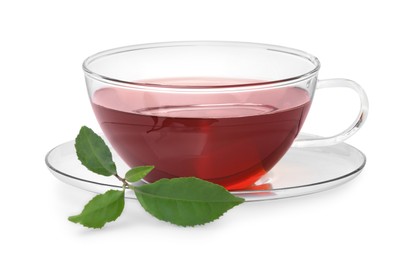 Photo of Glass cup of hot aromatic tea and green leaves on white background