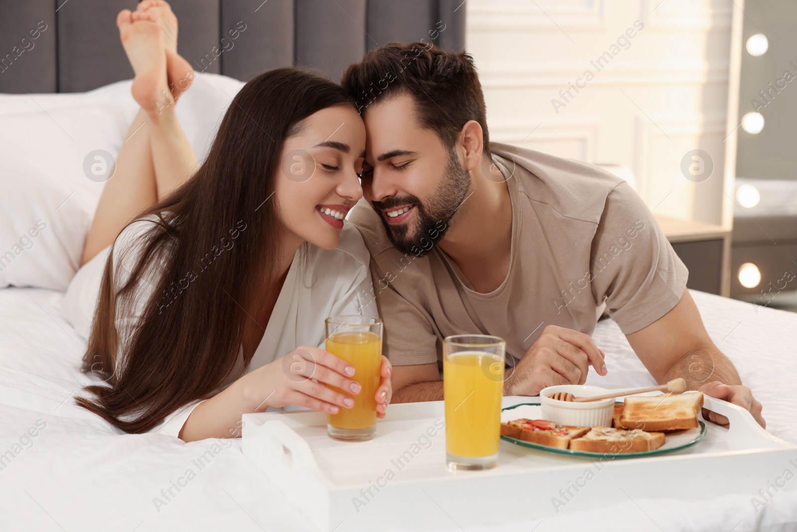 Photo of Happy couple having breakfast on bed at home