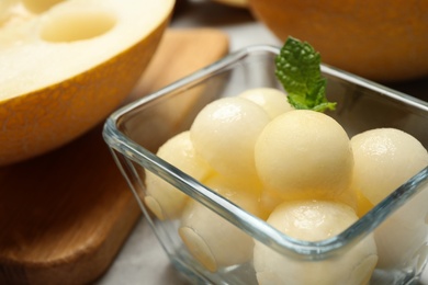 Photo of Melon balls with mint in glass bowl on table, closeup