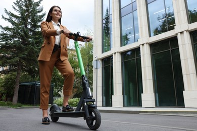 Photo of Businesswoman with modern electric kick scooter on city street, low angle view. Space for text