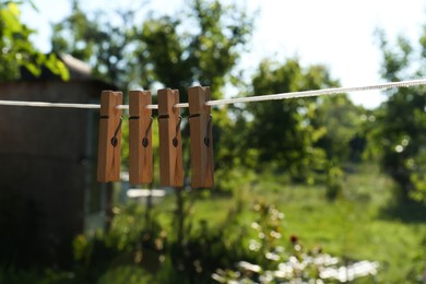Photo of Wooden clothespins hanging on washing line outdoors