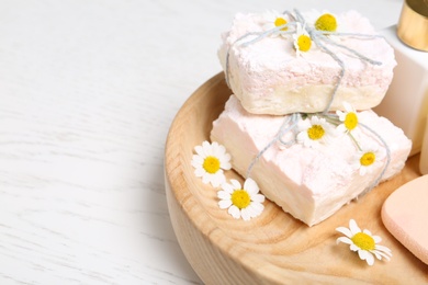 Chamomile flowers and soap bars on white table, closeup