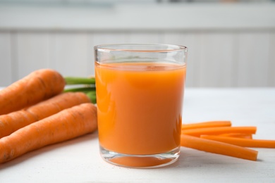 Photo of Glass with carrot juice and fresh vegetable on table