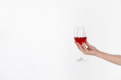 Woman holding glass of wine on light background