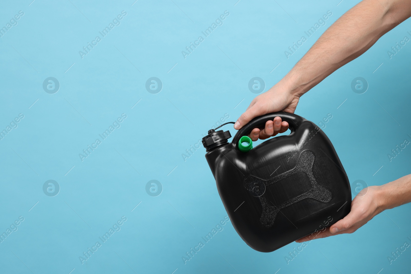 Photo of Man holding black canister on light blue background, closeup. Space for text