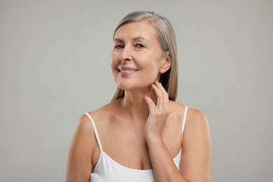 Photo of Beautiful woman touching her neck on grey background