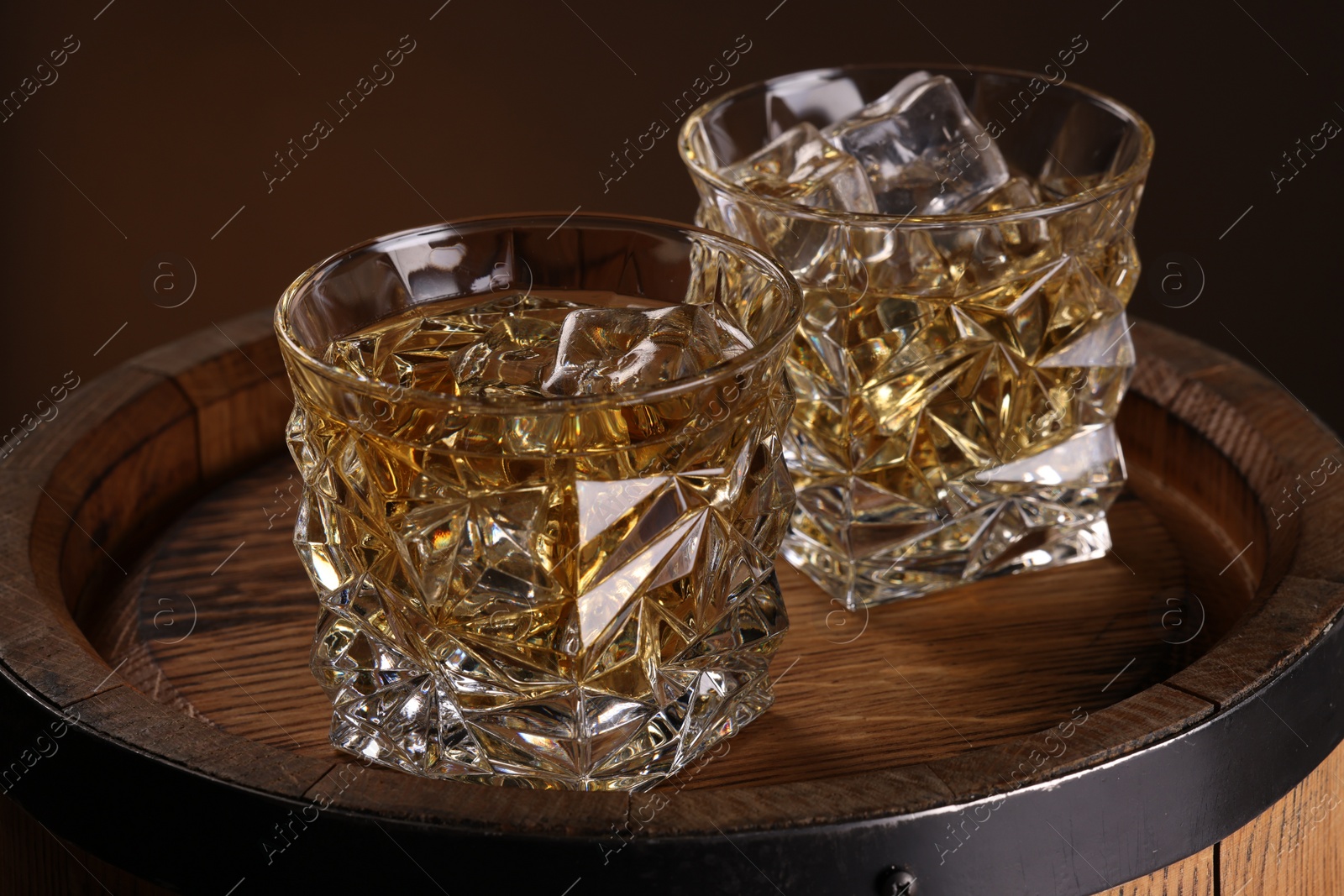 Photo of Whiskey in glasses on wooden barrel, closeup
