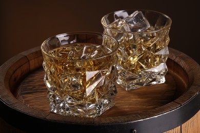 Whiskey in glasses on wooden barrel, closeup