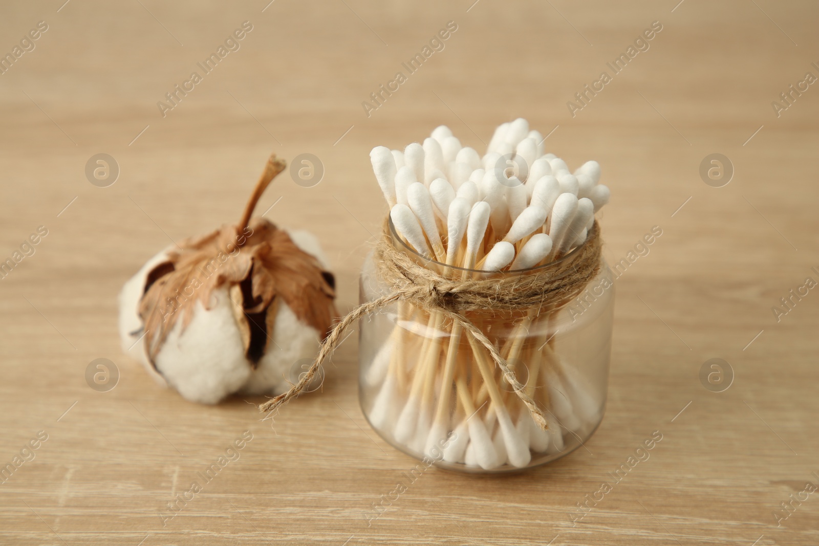 Photo of Cotton swabs and flower on wooden table, closeup