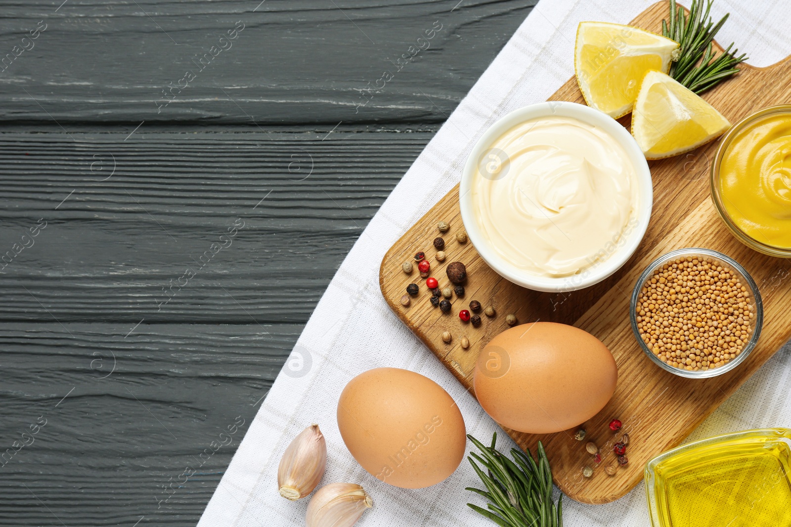 Photo of Bowl with fresh mayonnaise and ingredients on black wooden table, top view. Space for text