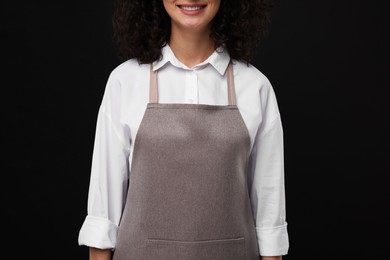 Woman wearing kitchen apron on black background, closeup. Mockup for design