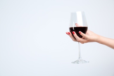 Woman holding glass of red wine on white background