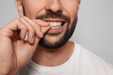 Photo of Man biting his nails on grey background, closeup