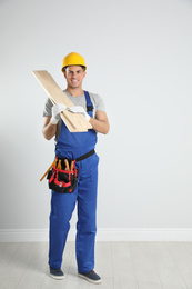 Photo of Handsome carpenter with wooden planks near light wall