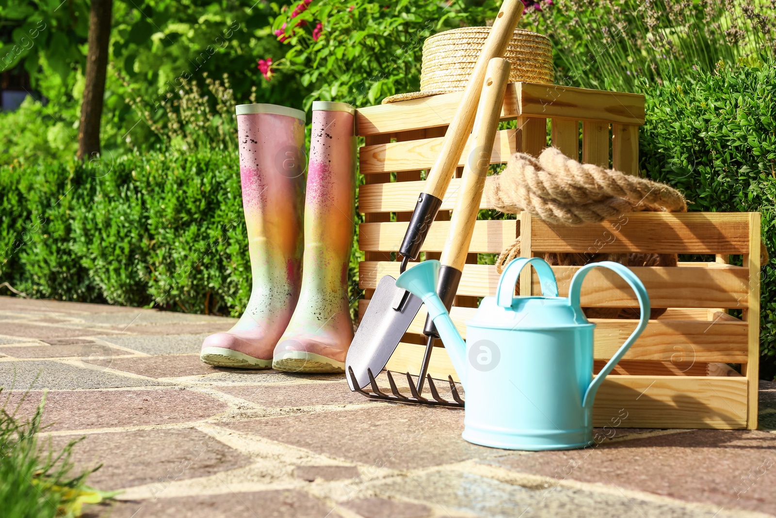 Photo of Wooden crates and gardening tools on stone path at backyard