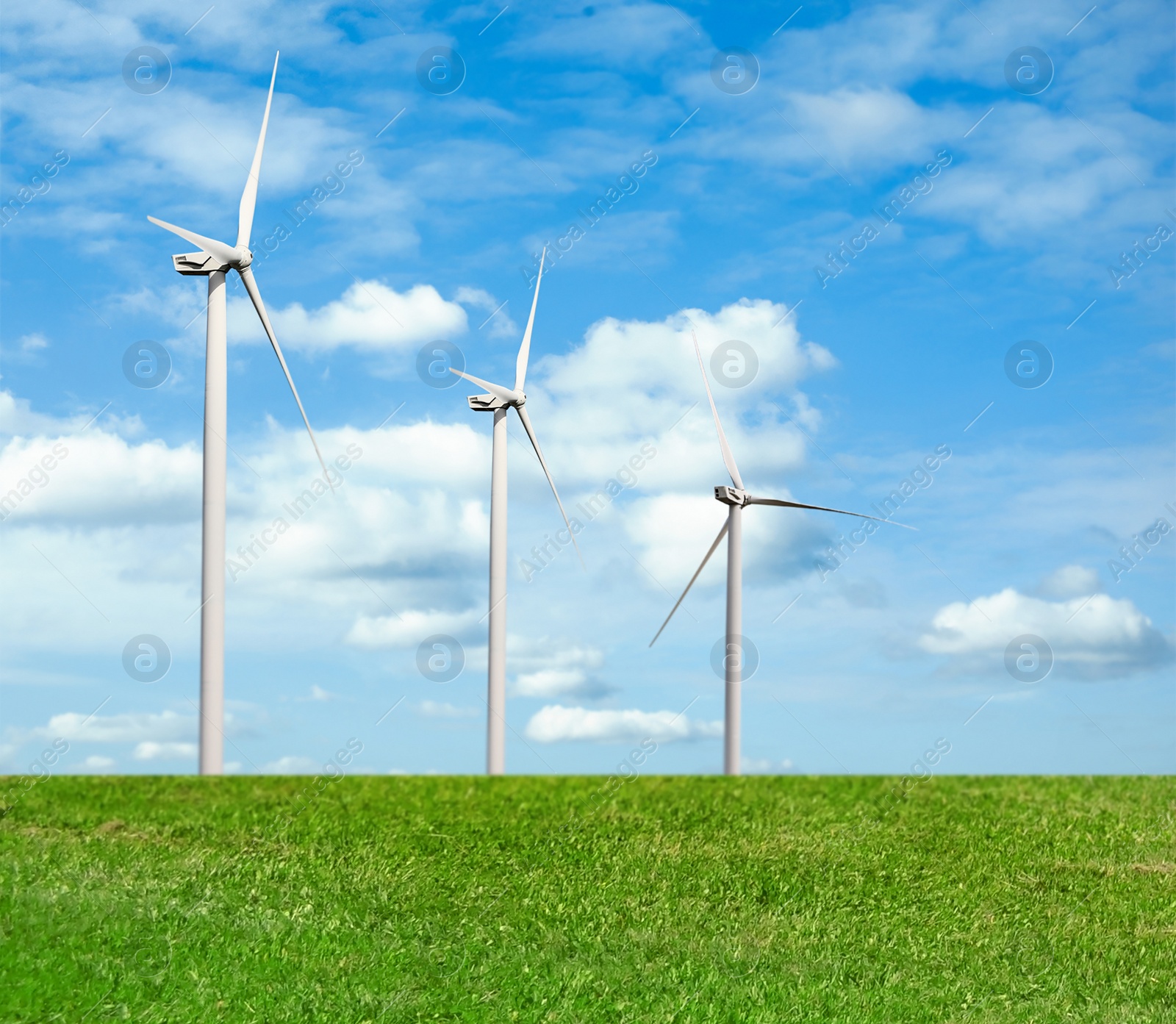 Image of Alternative energy source. Wind turbines in field under blue sky