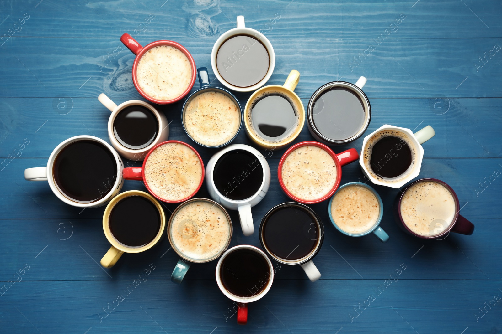 Photo of Many cups of different coffee drinks on blue wooden table, flat lay