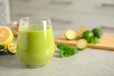 Photo of Fresh feijoa smoothie in glass on light grey table, closeup. Space for text