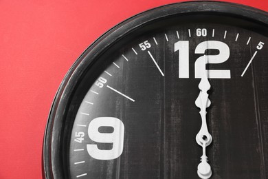Photo of Modern black clock on red background, top view
