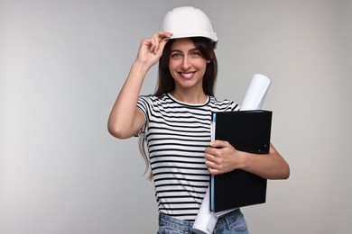 Photo of Architect in hard hat with draft and folder on light grey background