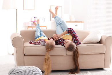 Photo of Happy mother and little daughter having fun on sofa at home