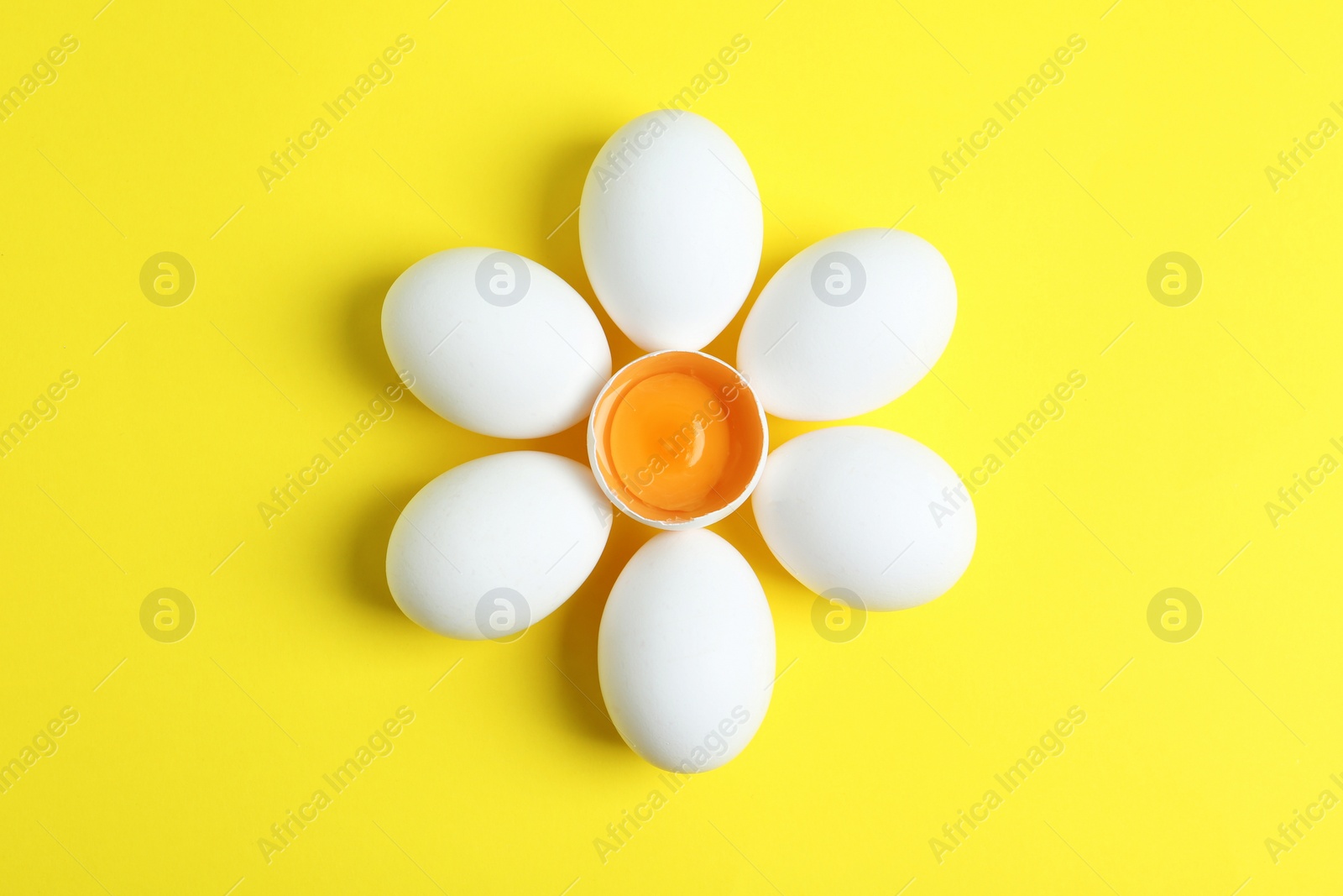 Photo of Fresh raw chicken eggs on yellow background, flat lay