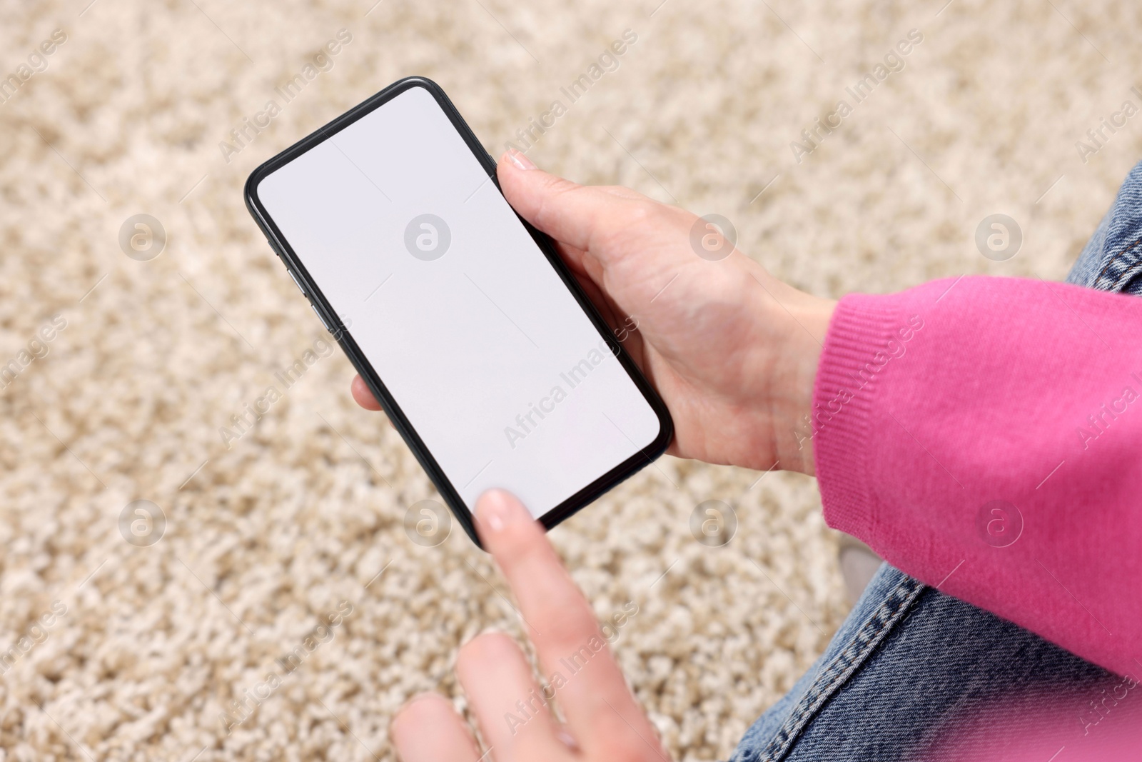 Photo of Woman using mobile phone on carpet, closeup