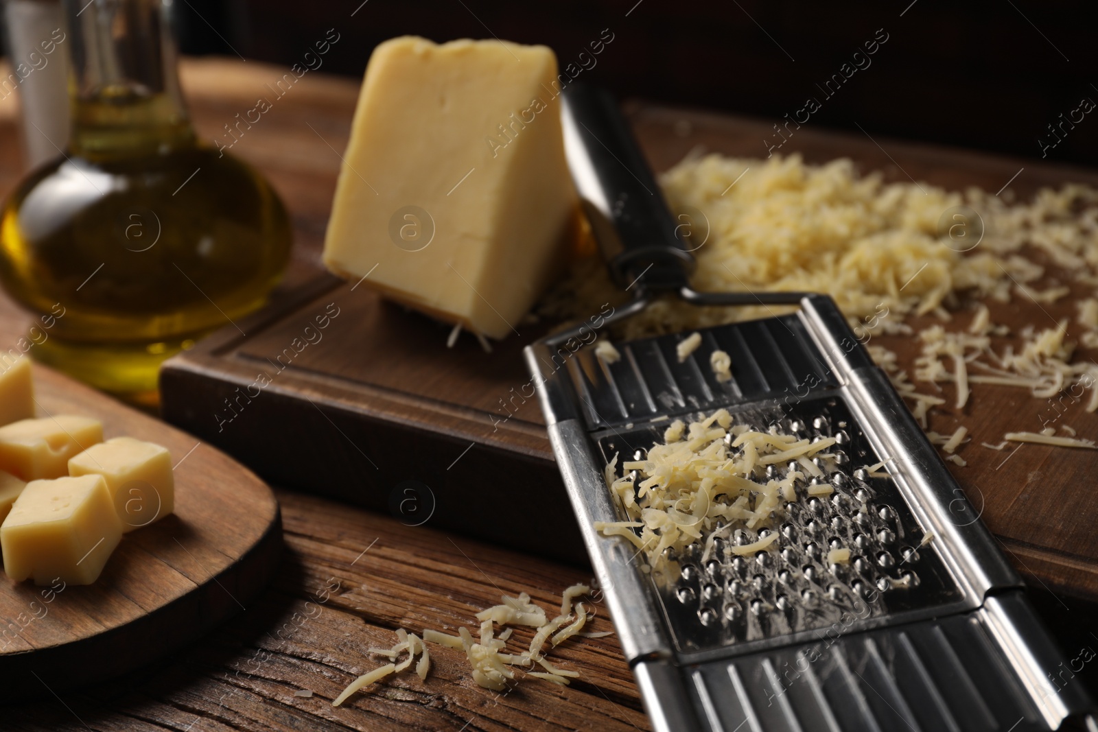 Photo of Different types of cheese and grater on wooden table, closeup