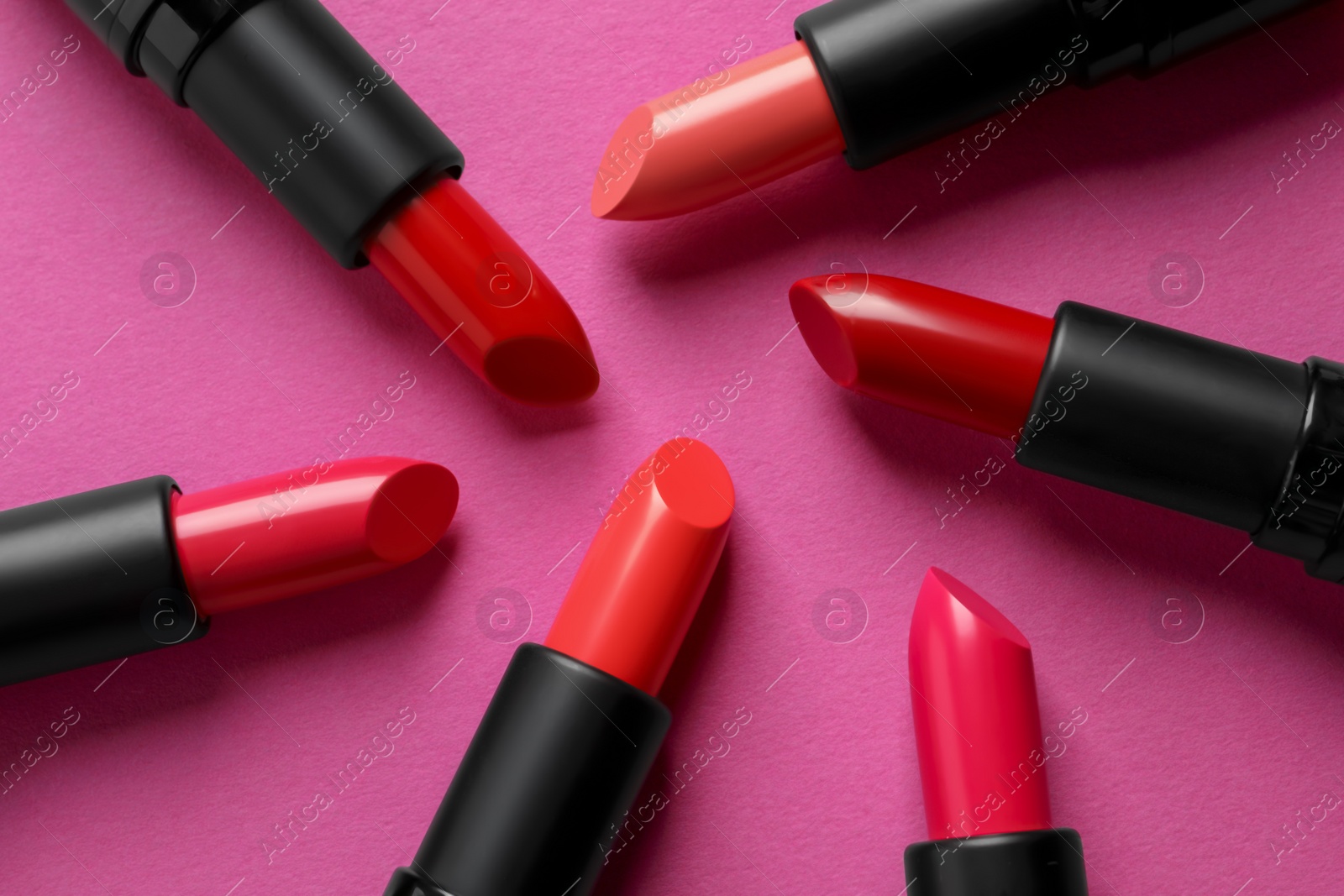 Photo of Beautiful lipsticks on pink background, flat lay