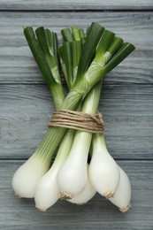 Bunch of green spring onions on grey wooden table, flat lay