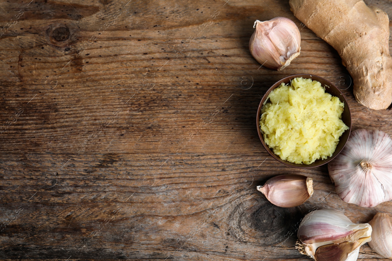 Photo of Fresh garlic, ginger and space for text on wooden table, flat lay. Natural cold remedies