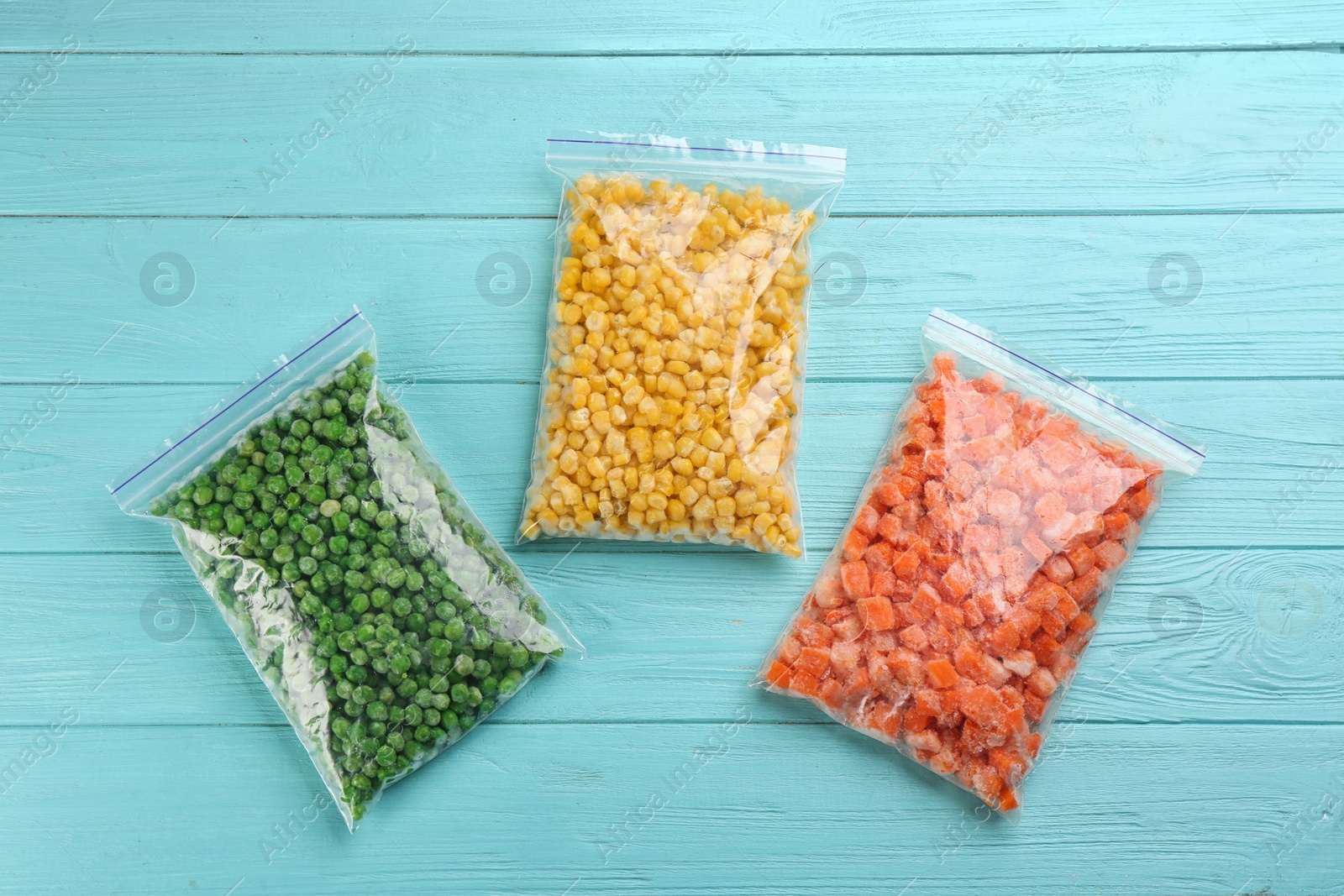 Photo of Different frozen vegetables on light blue wooden table, flat lay