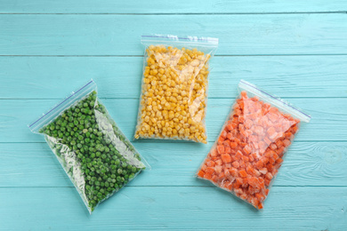 Different frozen vegetables on light blue wooden table, flat lay