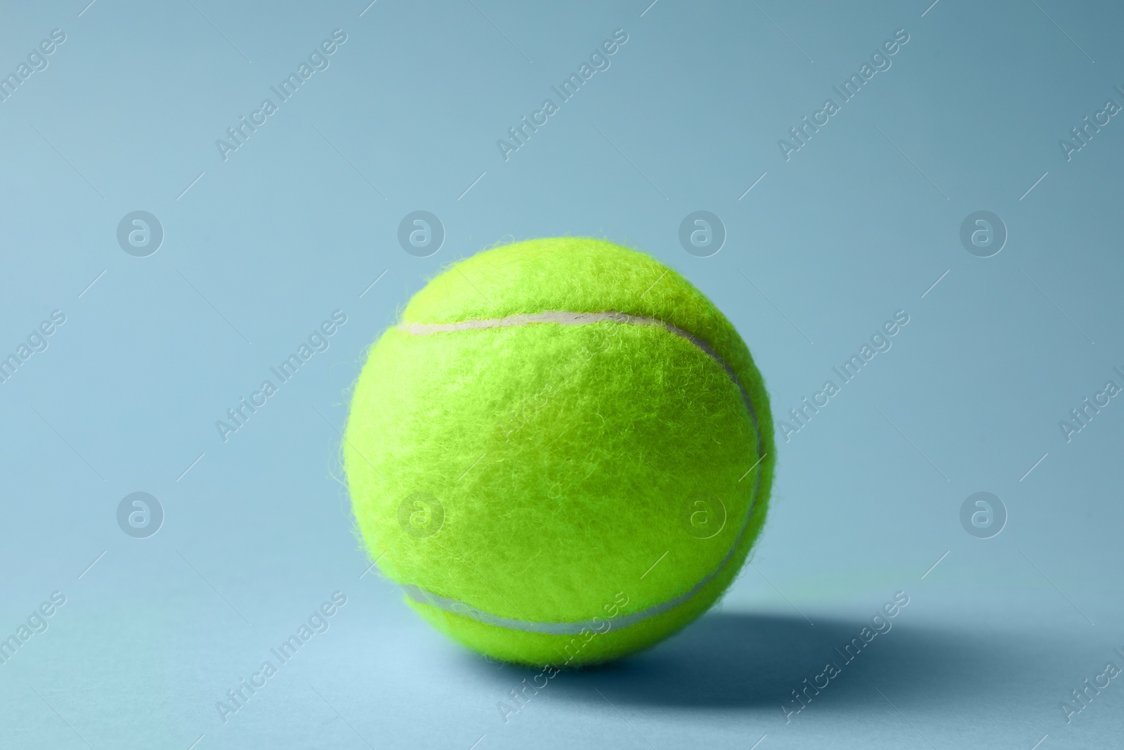 Photo of One tennis ball on light blue background