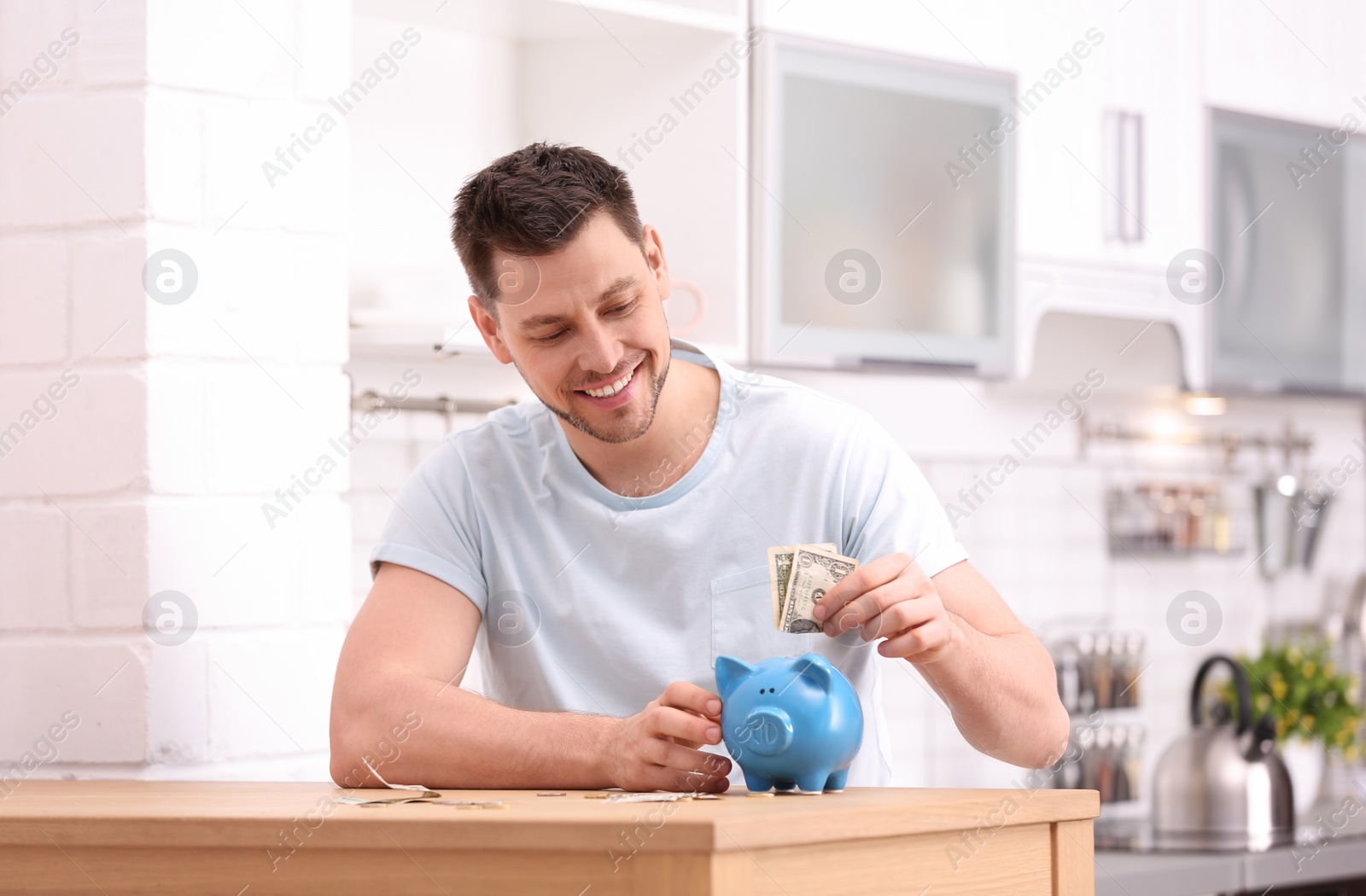 Photo of Man with piggy bank and money at home