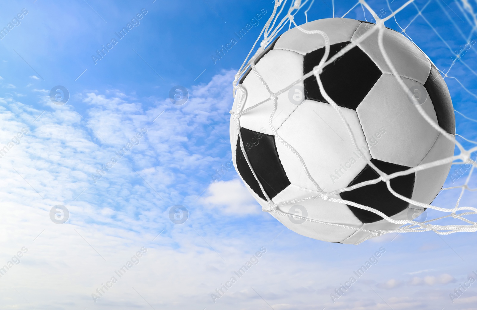 Image of Soccer ball in net against blue sky