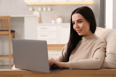 Photo of Woman working with laptop on sofa in kitchen