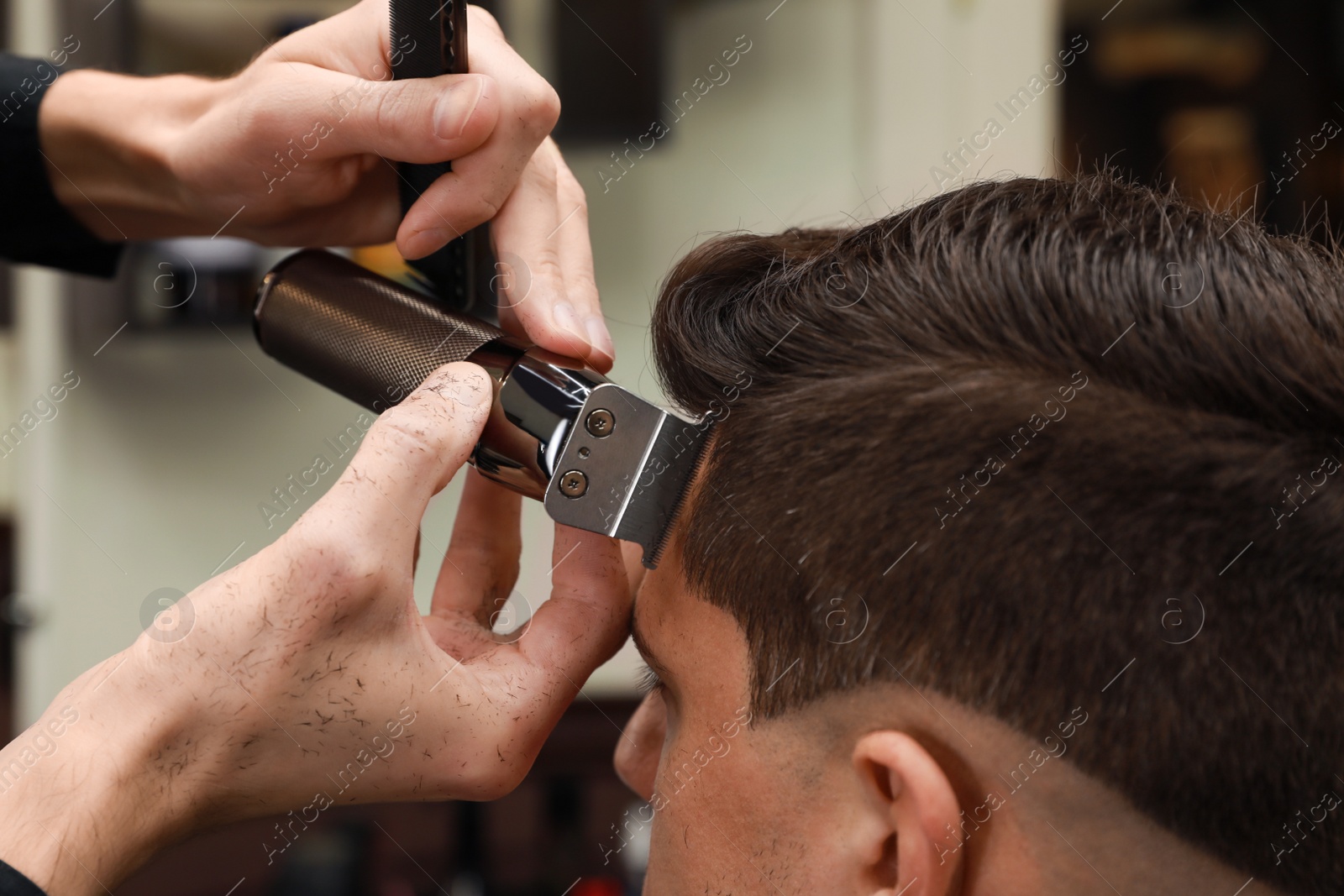 Photo of Professional hairdresser making stylish haircut in salon, closeup