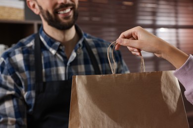 Photo of Worker giving paper bag to customer in cafe, closeup