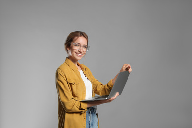 Photo of Portrait of young woman with modern laptop on grey background