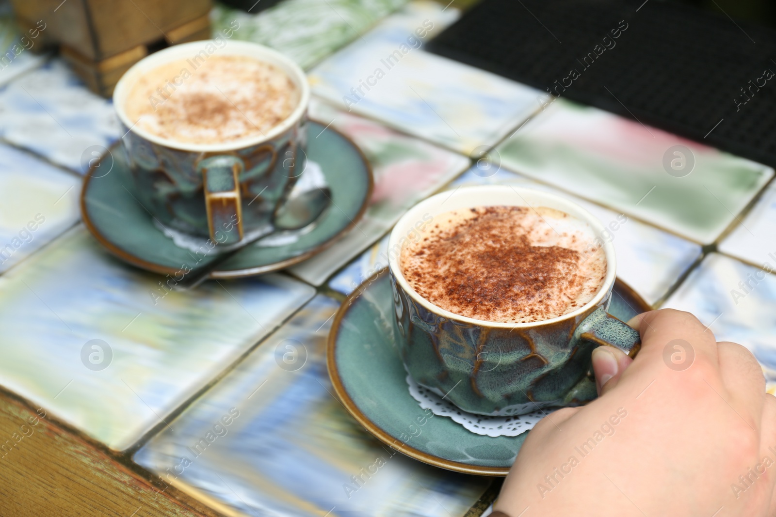 Photo of Woman with cups of fresh coffee at table, closeup