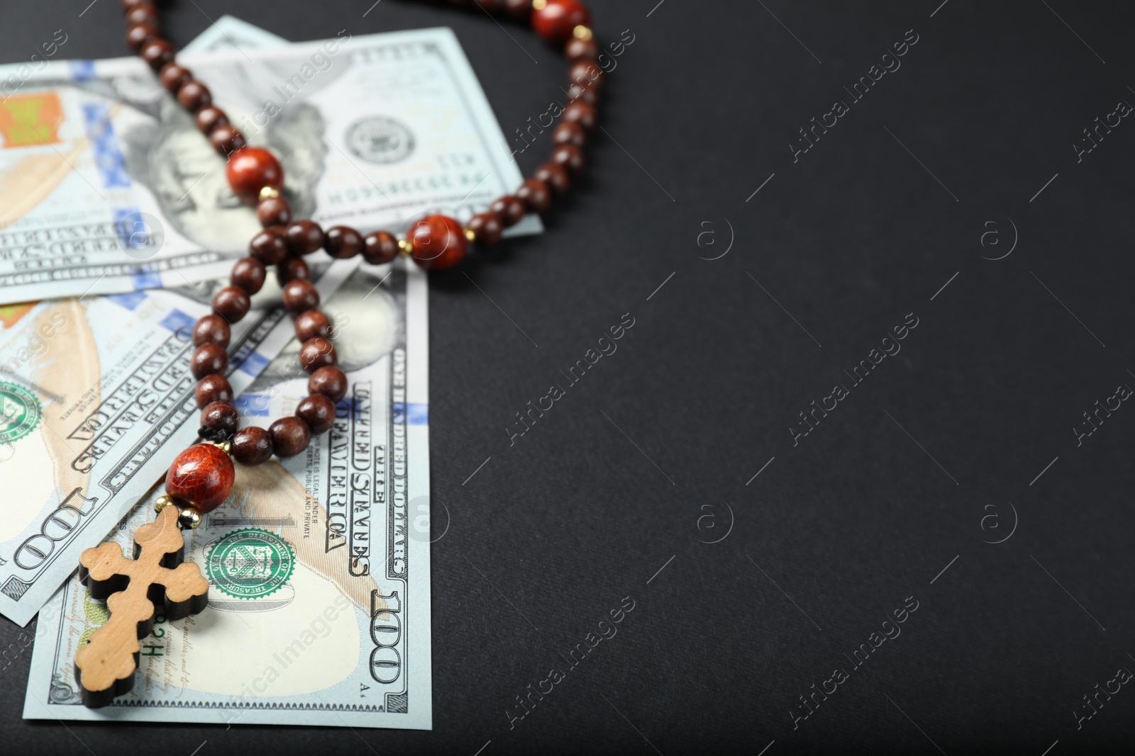 Photo of Dollars and prayer beads on grey table, space for text