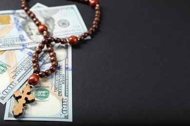 Photo of Dollars and prayer beads on grey table, space for text