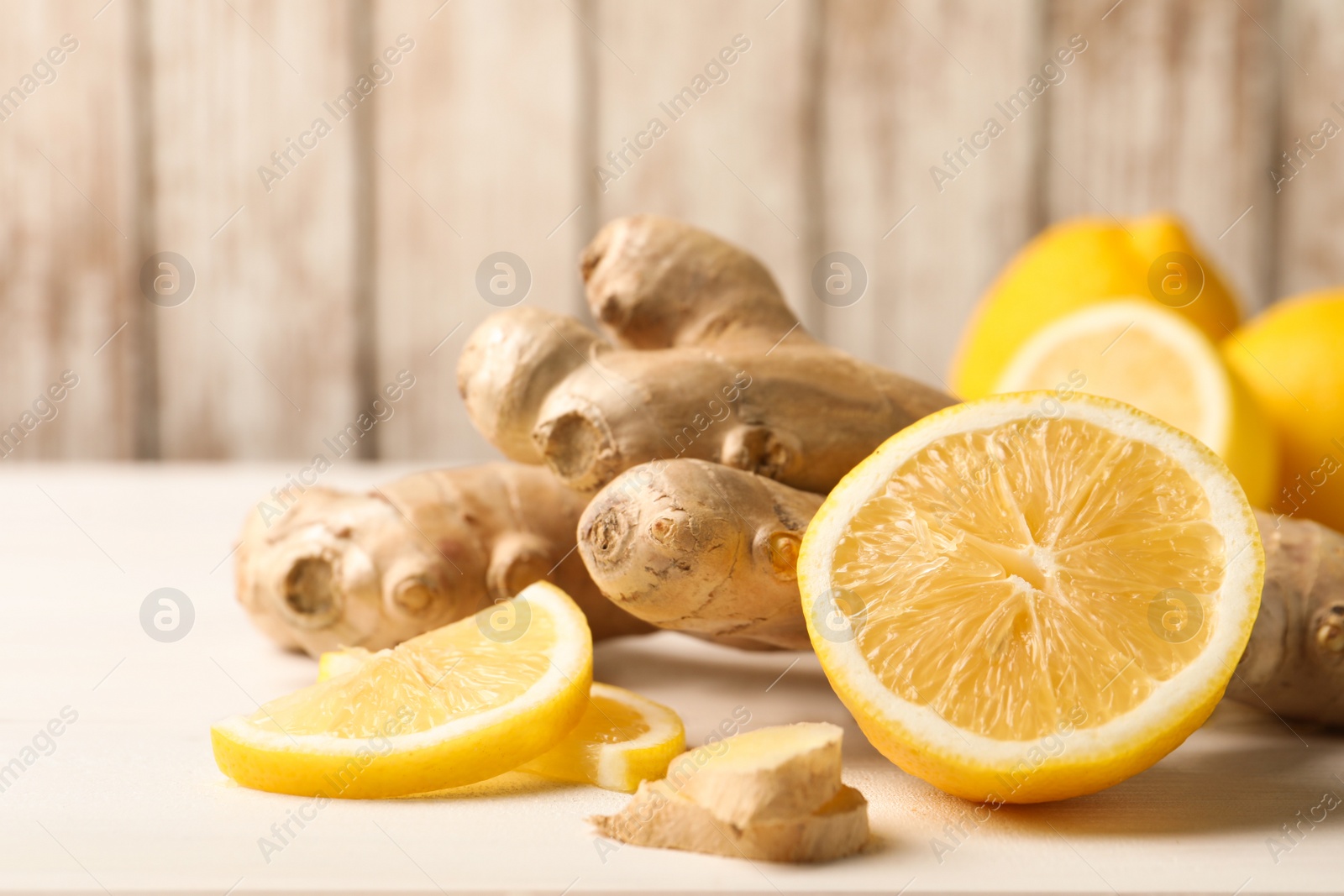 Photo of Fresh lemon and ginger on white table, closeup