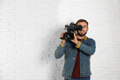 Photo of Operator with professional video camera near white brick wall, space for text