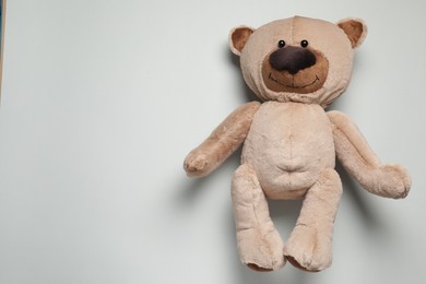 Cute teddy bear on light grey background, top view. Space for text