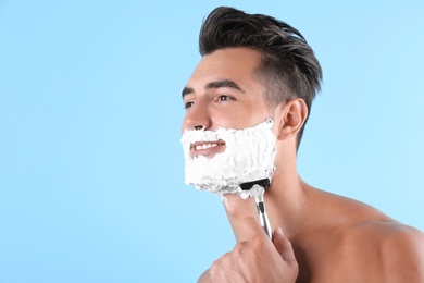 Photo of Handsome young man shaving on color background